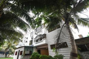 a white building with a palm tree in front of it at Hotel O New Alipore in Kolkata +34 photos