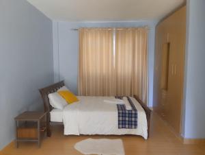 1 dormitorio con 1 cama con sábanas blancas y almohadas amarillas en Nyamus Home, en Hoeys Bridge