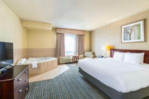a hotel room with a large bed and a tub at Quality Inn & Suites Yorkton in Yorkton