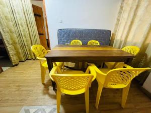 a dining table and chairs with yellow chairs around it at New Eagle Best Inn in Haputale