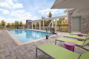 a swimming pool with tables and chairs next to a building at Home2 Suites By Hilton Sanford Orlando North in Sanford
