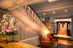a hallway with a staircase with a table and chairs at Bishop's Gate Hotel in Derry Londonderry