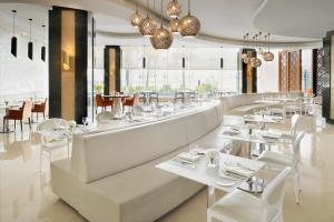 a restaurant with white tables and chairs and windows at Radisson Blu Hotel and Convention Center, Riyadh Minhal in Riyadh