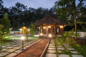 KodanadBethel Heritage Resort的花园中的一个晚上有灯的小房子