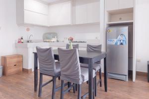 une cuisine avec une table avec des chaises et un réfrigérateur dans l'établissement Cozy Living 2BR Apartment at Casa de Parco By Travelio, à Tangerang