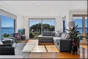 a living room with a couch and chairs and windows at Sandy Bay Sunrise Panorama House in Hobart