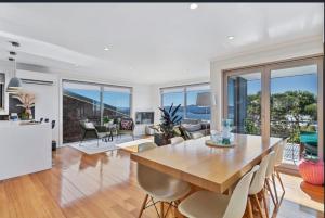 a dining room and living room with a table and chairs at Sandy Bay Sunrise Panorama House in Hobart