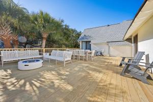 a deck with chairs and tables and palm trees at High Seas in DeBordieu Colony home by Peace Vacations in Georgetown
