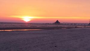 a sunset on the beach with a pier at Pension "Am Fischerweg" in Heringsdorf