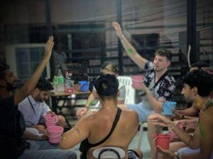 a group of men sitting around a table with their arms in the air at Seventeen Hostel in Haad Rin