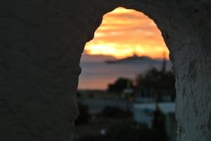 a view of the sunset through a hole in a rock at Kokalakis Hotel in Kefalos