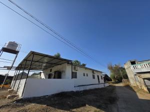 a small white building with a roof on a street at Sai homestay in Kevadia
