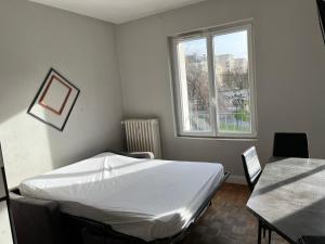 a bedroom with a bed and a table and a window at Appartements Caen Centre in Caen