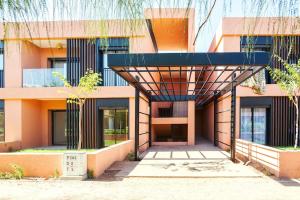 マラケシュにあるLivia cosy - Clim, Wifi, Jardin à 10min de l'Aéroportの日よけ付きの建物の外観