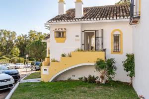 a white house with a yellow staircase in a parking lot at Casa Tropicana Family & Golf in Sitio de Calahonda