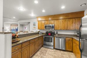 una cucina con armadietti in legno ed elettrodomestici in acciaio inossidabile di SNOW FLOWER 041 condo a Park City