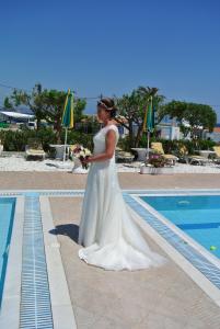 a woman in a wedding dress standing next to a swimming pool at Kokalakis Hotel in Kefalos