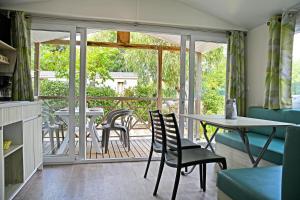 a living room with a table and chairs and a balcony at Camping Les Castors in Calvi
