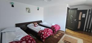 two beds in a room with red and white sheets at Pensiunea Bella Sacele in Săcele +36 photos
