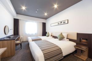 a hotel room with two beds and a desk at HOTEL MYSTAYS PREMIER Kanazawa in Kanazawa