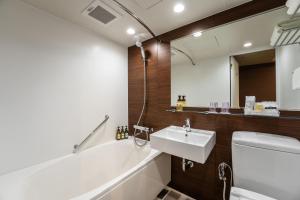 a bathroom with a sink and a tub and a mirror at HOTEL MYSTAYS PREMIER Kanazawa in Kanazawa