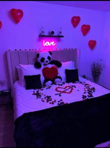 a stuffed panda bear sitting on a bed with a love sign at L’escapade Paris spa in Vauréal