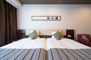 a hotel room with two beds and a chair at HOTEL MYSTAYS PREMIER Kanazawa in Kanazawa