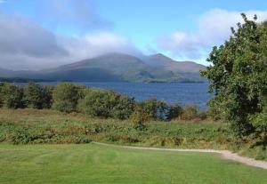 a field with a lake and a mountain in the background at Torc Hotel in Killarney