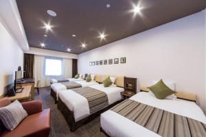 a hotel room with four beds and a flat screen tv at HOTEL MYSTAYS PREMIER Kanazawa in Kanazawa