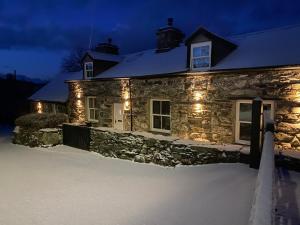 a stone house with lights on it in the snow at Garth Engan Private Self Contained B&B with Garden Area in Llanbedr