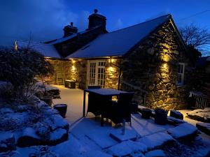 a stone house with lights on it in the snow at Garth Engan Private Self Contained B&B with Garden Area in Llanbedr