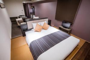 a bedroom with a white bed with orange pillows at HOTEL MYSTAYS PREMIER Kanazawa in Kanazawa