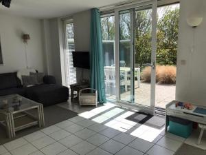 a living room with a couch and a sliding glass door at Comfortable 6-person holiday home in Sint Maartenszee