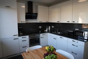 a kitchen with white cabinets and a table with a bowl of fruit at teck flat grande in Bissingen an der Teck