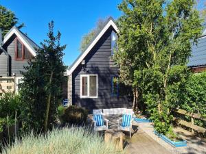 ein schwarzes Haus mit zwei blauen und weißen Stühlen in der Unterkunft Holiday home in Sint Maartenszee in Sint Maartenszee