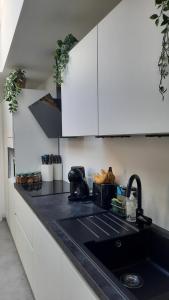 a kitchen with white cabinets and a black sink at Chambre d'hôte, la b&w in Liège