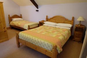 a bedroom with two beds and a table with a lamp at Brynderwen in Llangorse