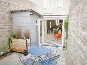 patio z niebieskimi krzesłami i garażem w obiekcie L'Héméra: Maison au coeur de Barfleur w mieście Barfleur