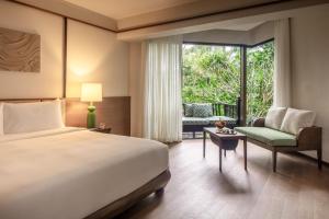 a bedroom with a bed and a chair and a window at Anantara Bophut Koh Samui Resort in Bophut