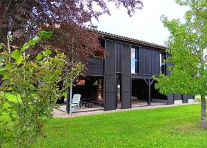 a black house with a white chair in a yard at Le Séchoir Aquitain, logement insolite in Dolmayrac