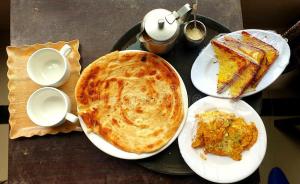 una mesa con dos platos de comida y un pastel en Subhan Residency, en Karachi