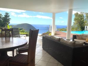 a patio with a table and chairs and a view of the ocean at Belle villa avec piscine à Caféière in Radelin +13 photos