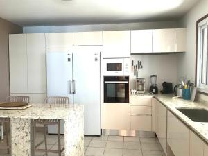 a kitchen with white cabinets and a white refrigerator at Belle villa avec piscine à Caféière in Radelin