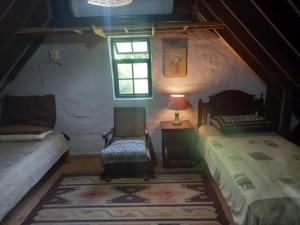 a bedroom with a bed and a chair and a window at Emerald Hill Cottage in Mount Pleasant
