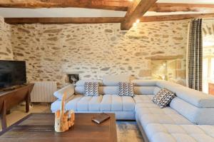 a living room with a blue couch and a tv at Newly renovated fort with panoramic landscape view jacuzzi & billiard in Leynhac