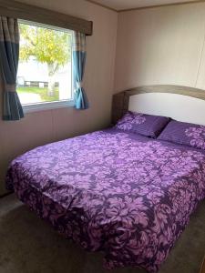 a purple bed in a bedroom with a window at 275 - Butlins Skegness, pet friendly and WiFi - Meadow Lakes Caravan & Lodge Hire in Ingoldmells +11 photos