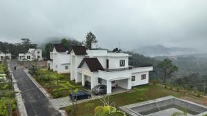 a row of white houses on a hill with a car at Highrange Villas in Vagamon
