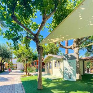 a house with a tree in the yard at Happy Camp mobile homes in Duca Amedeo Camping Village in Martinsicuro