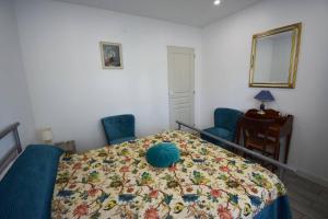 a bedroom with a bed and two chairs and a mirror at Appartement à Caudecoste, proche d'Agen in Caudecoste