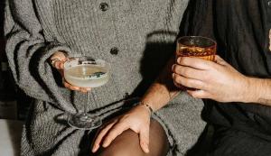a person holding a drink and a glass of alcohol at Hotel Shoshana - Adults Only in Eilat